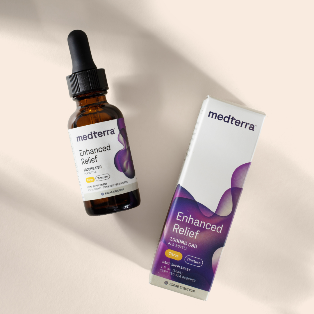 A dropper bottle and its packaging box labeled "Medterra Enhanced Relief Broad Spectrum CBD Oil" are placed on a light beige background. The bottle and box indicate it contains 1000 mg of CBD, with a citrus flavor. The tincture features a Broad Spectrum CBG blend from the hemp plant, promising an entourage effect with other ingredients.